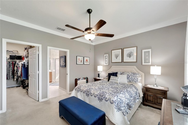 bedroom featuring a walk in closet, a closet, connected bathroom, light colored carpet, and ceiling fan