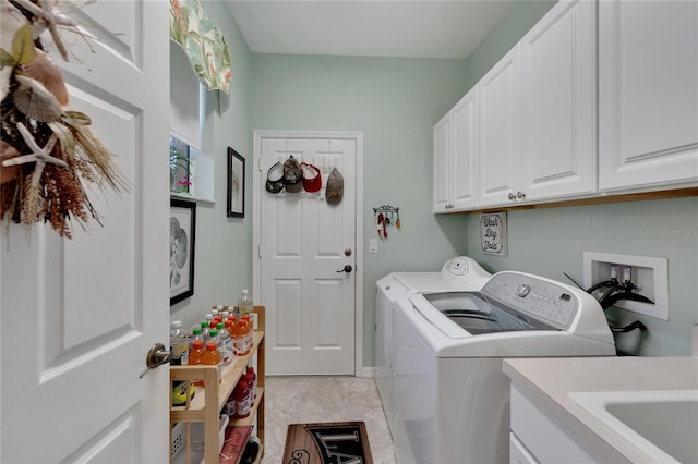 laundry room featuring washing machine and clothes dryer, cabinets, and light tile patterned floors