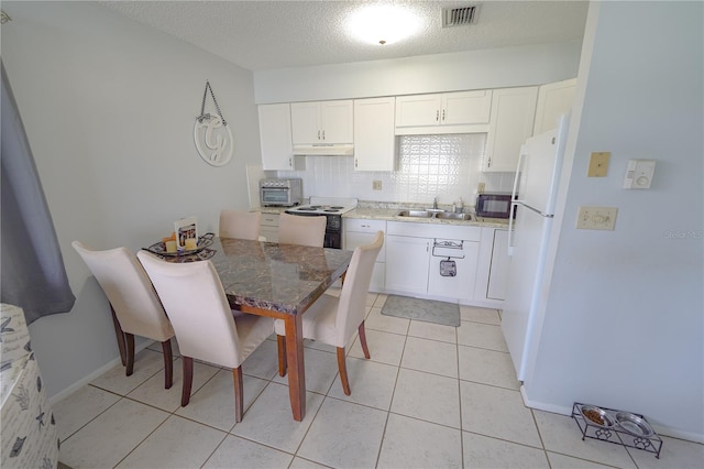 kitchen featuring white appliances, light tile patterned floors, decorative backsplash, and white cabinetry