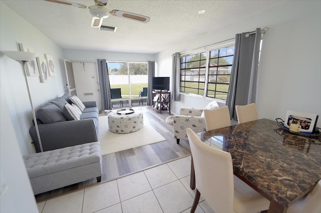 living room featuring a textured ceiling, ceiling fan, and light hardwood / wood-style floors