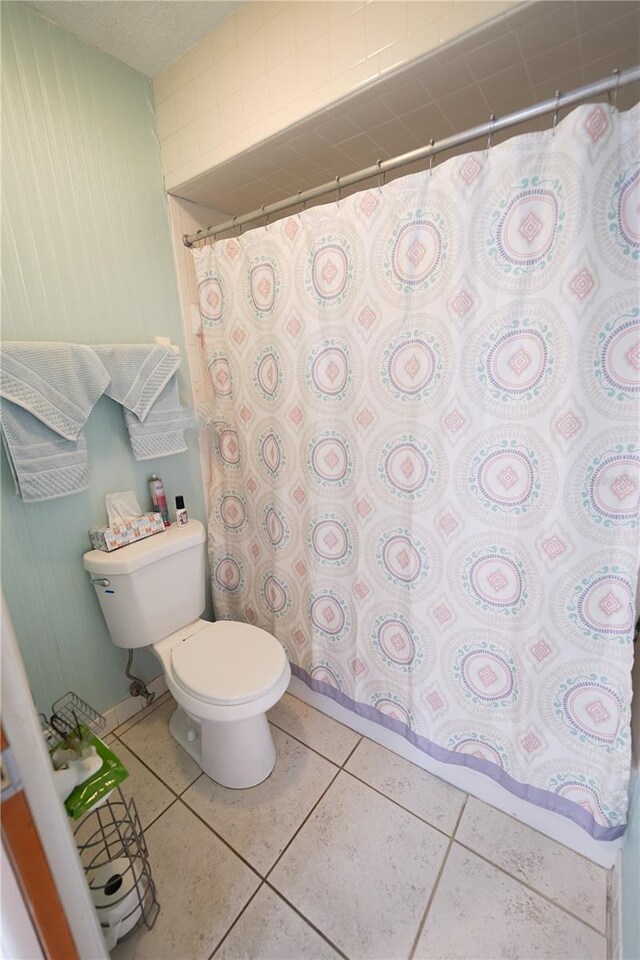 bathroom featuring a shower with curtain, tile patterned flooring, and toilet