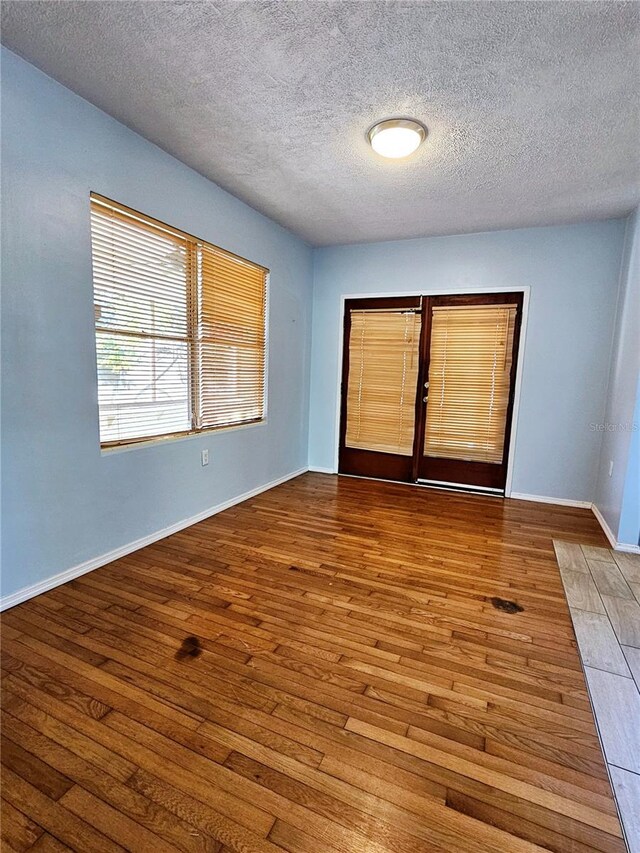 unfurnished room featuring baseboards, wood finished floors, and a textured ceiling
