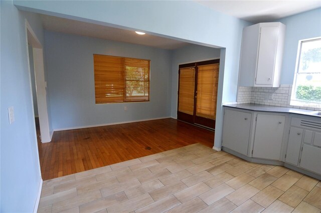 kitchen featuring light countertops, backsplash, white cabinets, and light wood-style floors