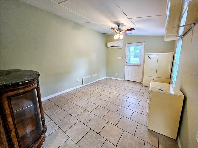 unfurnished dining area featuring light tile patterned floors, a ceiling fan, visible vents, an AC wall unit, and baseboards