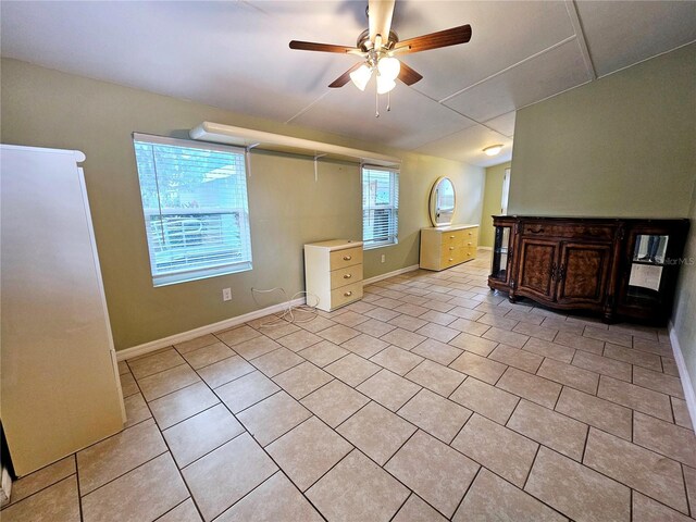 unfurnished living room featuring light tile patterned floors, baseboards, and a ceiling fan