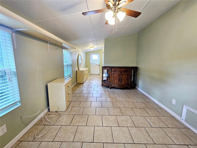 spare room featuring light tile patterned floors, ceiling fan, baseboards, and lofted ceiling