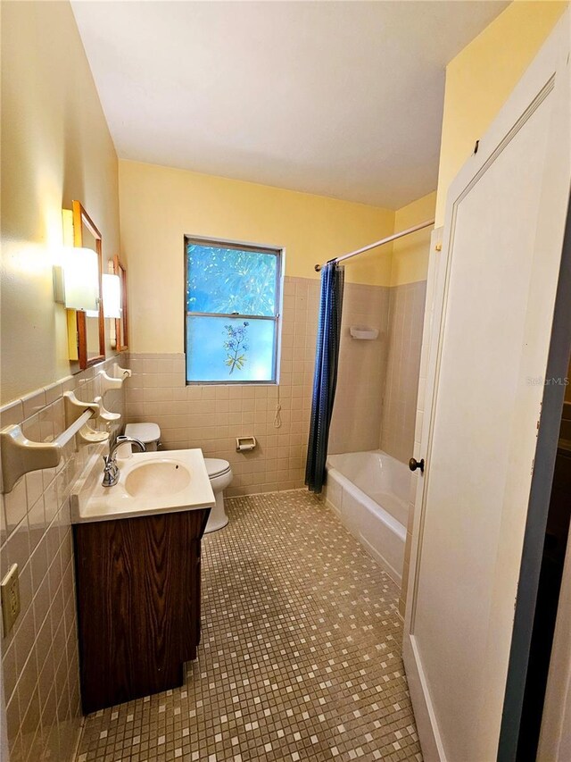 full bathroom with vanity, tile patterned floors, toilet, shower / bath combo with shower curtain, and tile walls