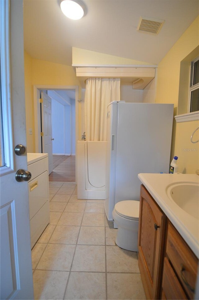full bath featuring visible vents, toilet, vanity, washer / dryer, and tile patterned flooring