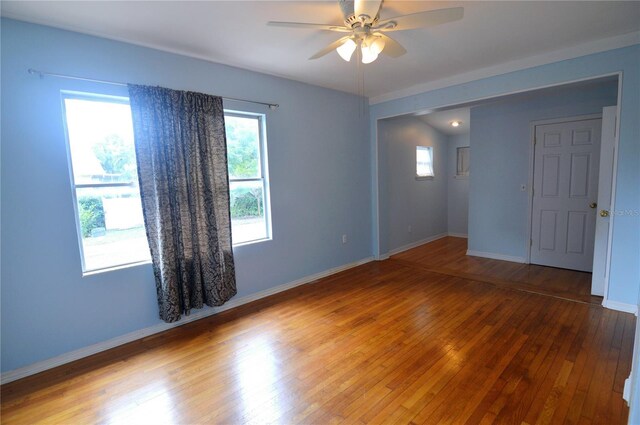 spare room featuring wood-type flooring, baseboards, and a ceiling fan