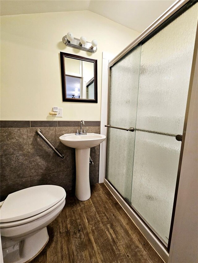 bathroom with tile walls, toilet, wainscoting, wood finished floors, and a stall shower