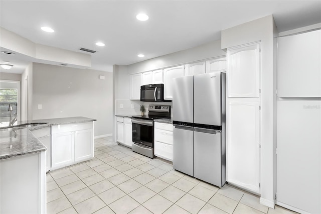 kitchen with stainless steel appliances, white cabinets, light stone counters, and sink