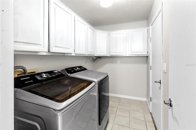 washroom with light tile patterned floors, washing machine and clothes dryer, and cabinets