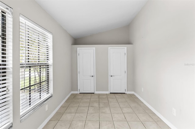 unfurnished bedroom featuring light tile patterned flooring and vaulted ceiling