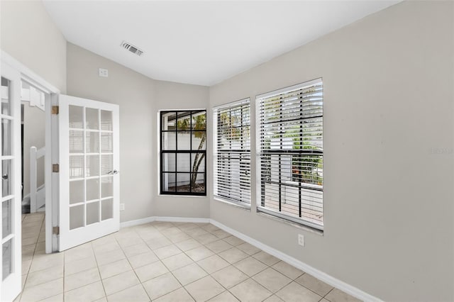 tiled spare room featuring lofted ceiling and french doors