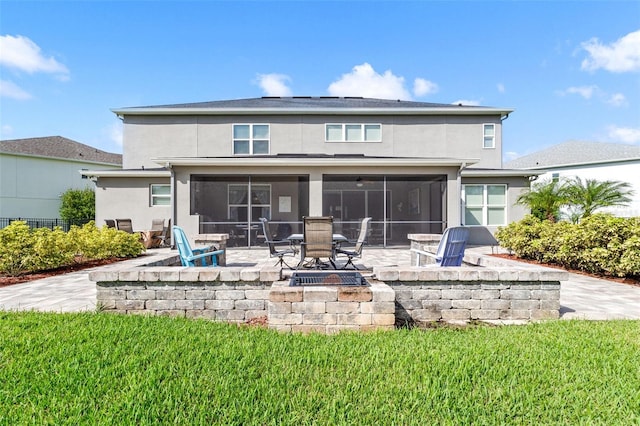 back of property with a lawn, a sunroom, an outdoor fire pit, and a patio area