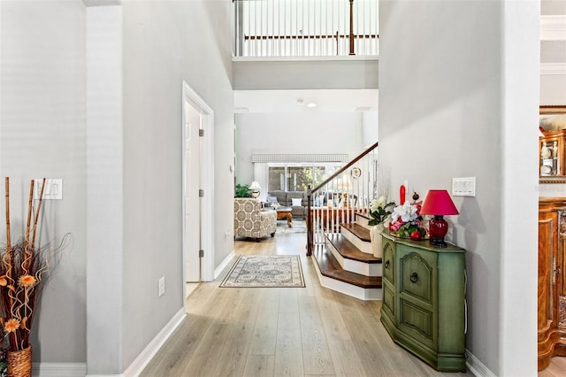 foyer entrance featuring light wood-type flooring and a towering ceiling