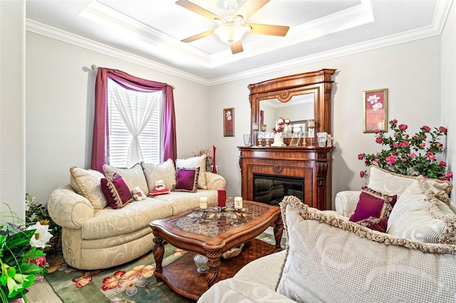 living room featuring ceiling fan, a raised ceiling, and ornamental molding