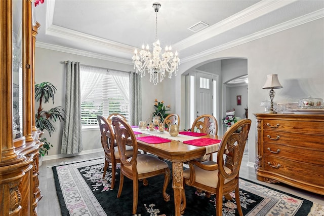 dining room featuring crown molding, hardwood / wood-style floors, a chandelier, and a raised ceiling