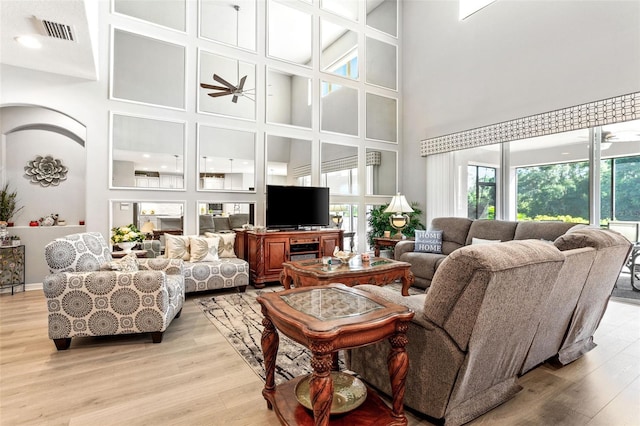 living room with light hardwood / wood-style floors and a towering ceiling