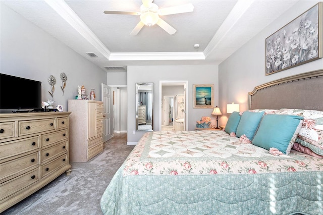 carpeted bedroom with ornamental molding, a tray ceiling, ceiling fan, and ensuite bath