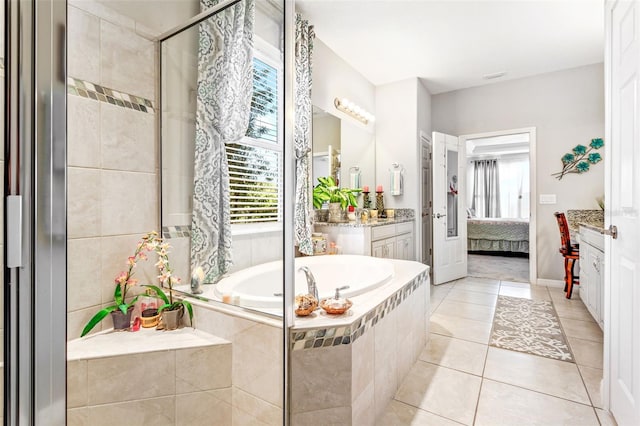 bathroom with tile patterned flooring, tiled tub, and vanity