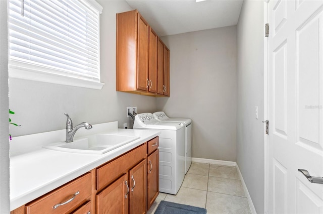 laundry room with cabinets, washing machine and dryer, light tile patterned floors, and sink