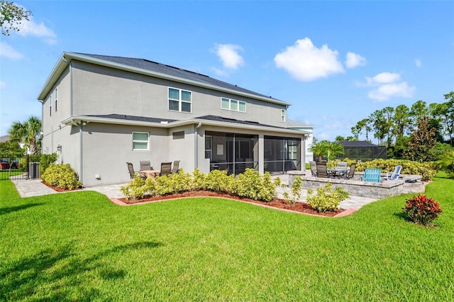 back of property with a lawn, a sunroom, and a patio area