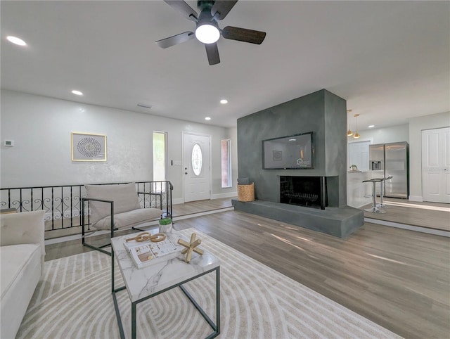 living room featuring ceiling fan, a fireplace, and light hardwood / wood-style flooring