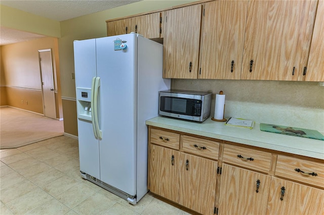 kitchen with white fridge with ice dispenser, a textured ceiling, and light brown cabinetry