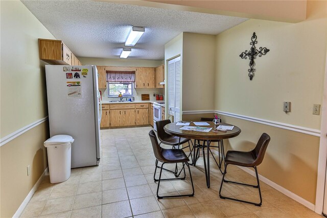 tiled dining area with a textured ceiling and sink