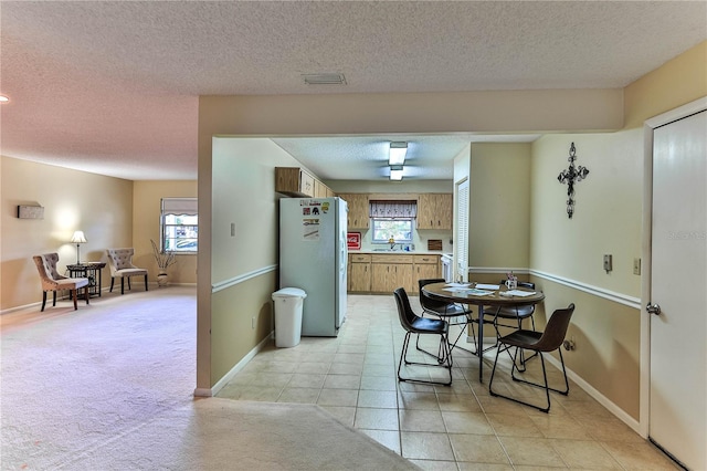 carpeted dining room featuring sink and a textured ceiling