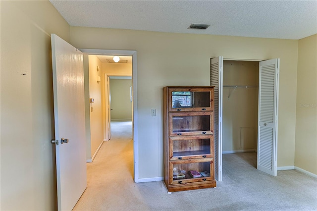 corridor with a textured ceiling and light colored carpet