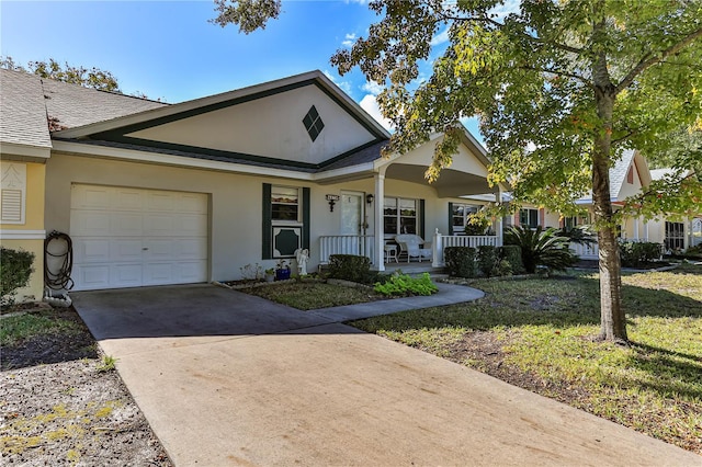 view of front of home featuring covered porch, a garage, and a front lawn