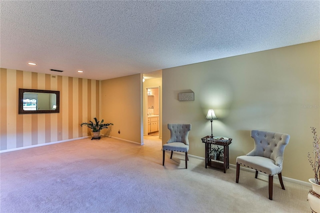 sitting room featuring carpet and a textured ceiling