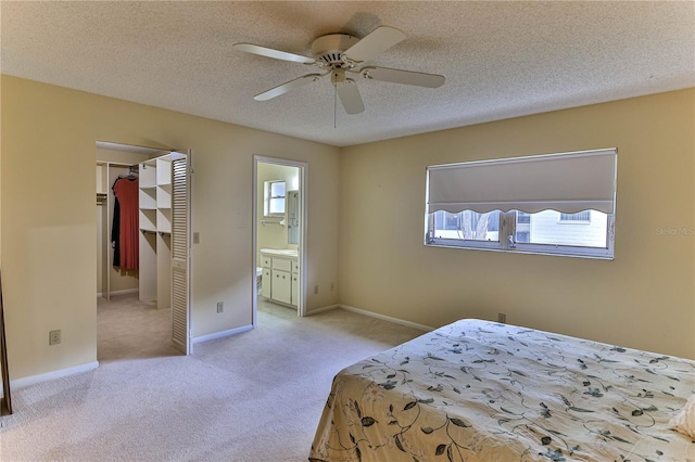 carpeted bedroom featuring a textured ceiling, ensuite bathroom, a closet, and ceiling fan