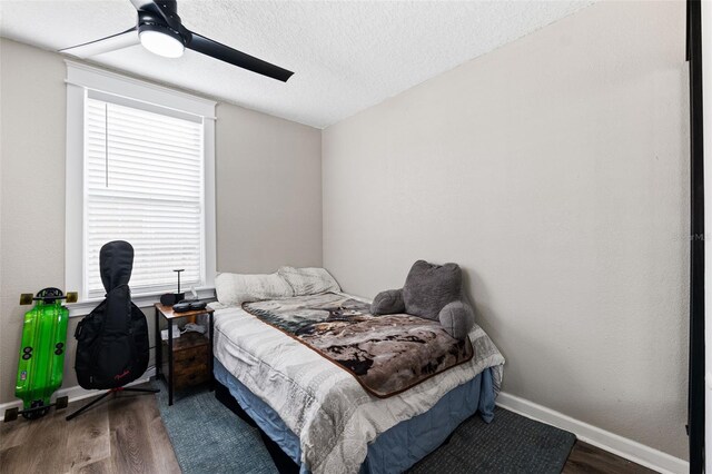 bedroom featuring ceiling fan, dark hardwood / wood-style floors, vaulted ceiling, and a textured ceiling