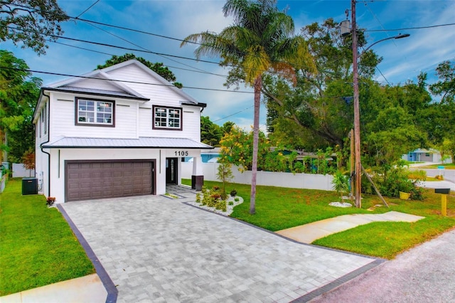 view of front of property with fence, an attached garage, decorative driveway, central AC unit, and a front lawn