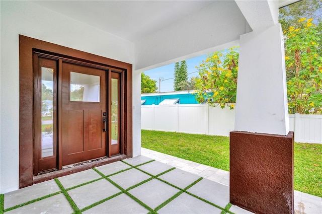 property entrance featuring a yard, stucco siding, fence, and a patio area