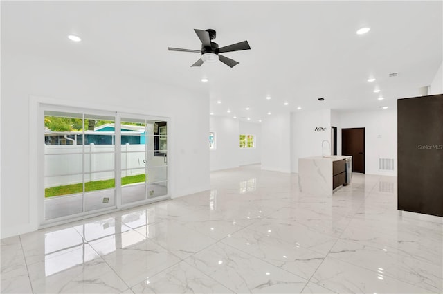 unfurnished living room featuring ceiling fan and sink