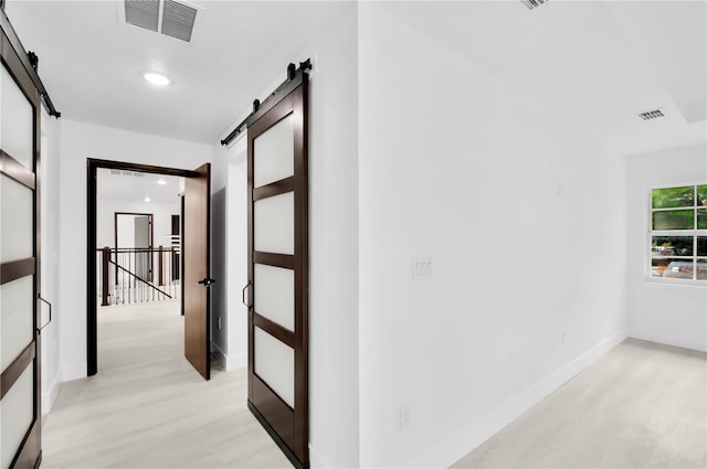 hallway with a barn door and light wood-type flooring