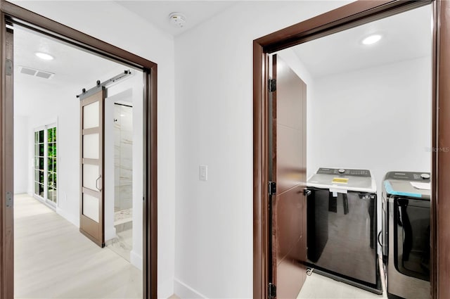 laundry area with a barn door and washing machine and dryer