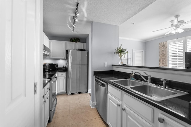 kitchen with dark countertops, a sink, appliances with stainless steel finishes, and light tile patterned flooring