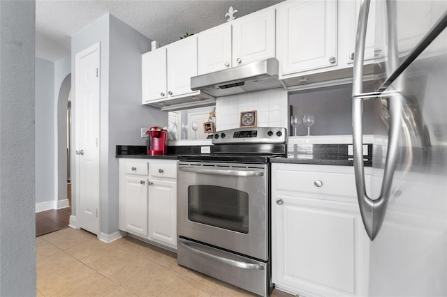 kitchen with a textured ceiling, backsplash, light tile patterned floors, appliances with stainless steel finishes, and white cabinets