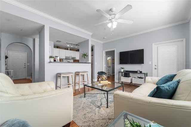 living room featuring ceiling fan, a textured ceiling, wood-type flooring, and ornamental molding