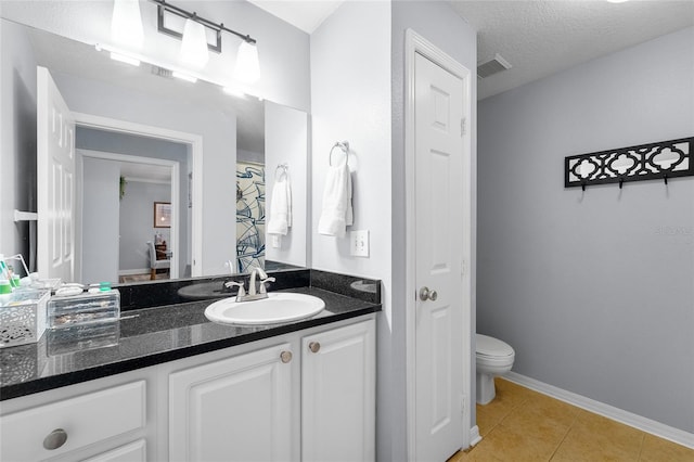 bathroom featuring vanity, toilet, tile patterned flooring, and a textured ceiling