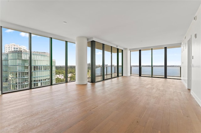 interior space with floor to ceiling windows, light wood-style flooring, and a water view