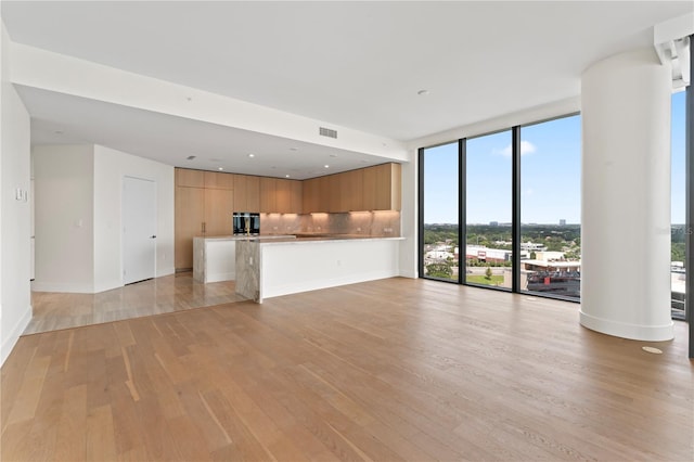 unfurnished living room featuring a wall of windows and light wood-type flooring