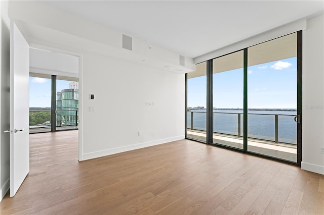 spare room with light hardwood / wood-style floors, expansive windows, and a water view