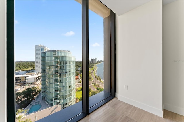 doorway with a water view, expansive windows, and hardwood / wood-style floors