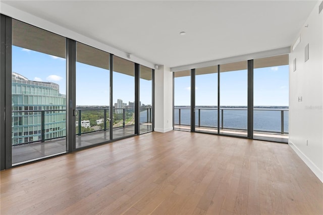 spare room with a wealth of natural light, light hardwood / wood-style flooring, and a water view